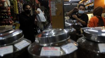 Pramuniaga melayani pembeli biji kopi di Toko Dunia Kopi, Pasar Santa, Jakarta, Rabu (23/2/2022). [Suara.com/Angga Budhiyanto]