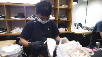 Kru membersihkan sepatu pelanggan di Cleaning Shoes Kicks Kemon, Haji Nawi, Jakarta Selatan, Rabu (23/2/2022). [Suara.com/Alfian Winanto]