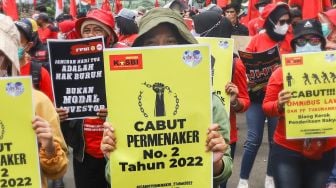 Massa buruh membawa poster dan spanduk berisi tuntutan saat menggelar aksi unjuk rasa di depan gedung Kementerian Tenaga Kerja (Kemenaker) di Setia Budi, Jakarta Selatan, Rabu (23/2/2022). [Suara.com/Alfian Winanto]