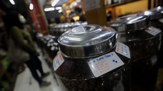 Deretan toples berisi biji kopi dipajang di Toko Dunia Kopi, Pasar Santa, Jakarta, Rabu (23/2/2022). [Suara.com/Angga Budhiyanto]