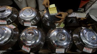 Pramuniaga mengemas biji kopi pesanan pelanggan di Toko Dunia Kopi, Pasar Santa, Jakarta, Rabu (23/2/2022). [Suara.com/Angga Budhiyanto]