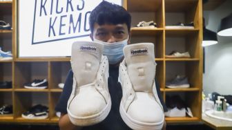 Kru menunjukkan sepatu pelanggan yang sudah dibersihkan di Cleaning Shoes Kicks Kemon, Haji Nawi, Jakarta Selatan, Rabu (23/2/2022). [Suara.com/Alfian Winanto]