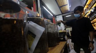 Pramuniaga menimbang biji kopi pesanan pelanggan di Toko Dunia Kopi, Pasar Santa, Jakarta, Rabu (23/2/2022). [Suara.com/Angga Budhiyanto]