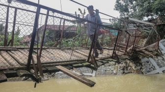 Warga memaksakan diri melintasi jembatan rusak di Desa Sukarasa, Tanjung Sari, Kabupaten Bogor, Jawa Barat, Kamis (24/2/2022). ANTARA FOTO/Yulius Satria Wijaya