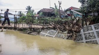 Warga memaksakan diri melintasi jembatan rusak di Desa Sukarasa, Tanjung Sari, Kabupaten Bogor, Jawa Barat, Kamis (24/2/2022). ANTARA FOTO/Yulius Satria Wijaya