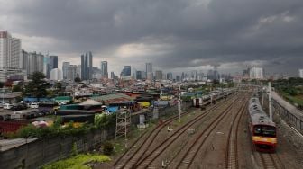 Rangkaian KRL Commuter Line melintas di dekat permukiman padat penduduk di kawasan Tanah Abang, Jakarta, Sabtu (26/2/2022). [Suara.com/Angga Budhiyanto]