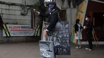 Seniman melakukan aksi pameran seni jalanan atau 'street art' di kawasan Dukuh Atas, Jakarta, Sabtu (26/2/2022). [Suara.com/Angga Budhiyanto]