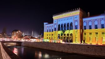 Balai kota Sarajevo yang menyala dengan warna bendera Ukraina di Sarajevo, Bosnia-Herzegovina, Kamis (24/2/2022). [ELVIS BARUKCIC / AFP] 