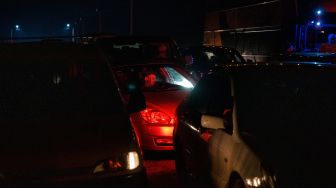 Orang-orang duduk di mobil mereka sambil menunggu untuk menyeberang dari Ukraina ke Polandia di perbatasan Korczowa-Krakovets, Sabtu (26/2/2022). [Dimitar DILKOFF/AFP]
