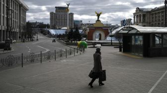 Seorang warga sipil melintasi alun-alun Maidan, Kyiv, Ukraina, Minggu (27/2/2022). [Aris Messinis / AFP]