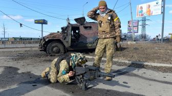 Pejuang Pertahanan Teritorial Ukraina menguji peluncur granat otomatis yang diambil dari kendaraan infanteri Rusia GAZ Tigr yang hancur setelah pertempuran di Kharkiv, Ukraina, Minggu (27/2/2022). [Sergey BOBOK / AFP] 