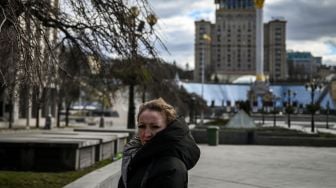 Seorang warga sipil melintasi alun-alun Maidan, Kyiv, Ukraina, Minggu (27/2/2022). [Aris Messinis / AFP]