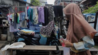 Warga berjalan di dekat permukiman padat penduduk di kawasan Kebon Melati, Jakarta, Kamis (3/3/2022). [Suara.com/Angga Budhiyanto]