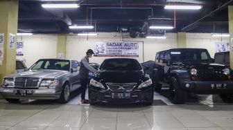 Pekerja membersihkan mobil di bursa mobil bekas, blok M, Jakarta Selatan, Jumat (4/3/2022). [Suara.com/Alfian Winanto]