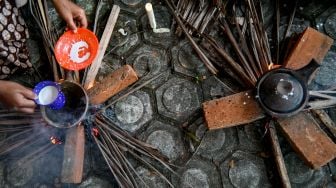 Orang - orang memasak serabi (apam) makanan tradisional Indonesia ssaat Festival Kuliner Tradisional Tet Apam (memasak serabi) di Anjungan Pekan Kebudayaan Aceh (PKA) Taman Ratu Safiatuddin, Banda Aceh, Aceh, Sabtu (5/3/2022). [CHAIDEER MAHYUDDIN / AFP]
