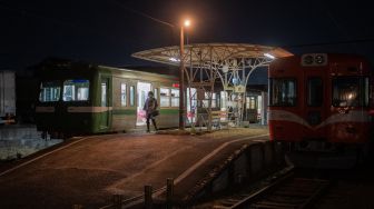 Seorang Penumpang turun di stasiun usai menaiki kereta yang populer untuk tur wisata malam hari yang melintasi jalur kereta Gakunan melalui kawasan industri di Fuji, prefektur Shizuoka, Jepang, Sabtu (26/2/2022). [Philip FONG / AFP]