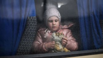 Seorang gadis bermain dengan mainan saat dia menunggu di dalam bus mini menuju kota Uzhhorod di dekat perbatasan dengan Slovakia di stasiun kereta Lviv, Ukraina barat, Sabtu (5/3/2022). [Daniel LEAL / AFP]