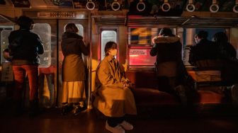 Penumpang menaiki kereta yang populer untuk tur wisata malam hari yang melintasi jalur kereta Gakunan melalui kawasan industri di Fuji, prefektur Shizuoka, Jepang, Sabtu (26/2/2022). [Philip FONG / AFP]
