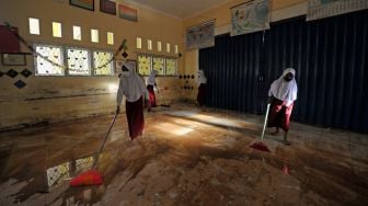 Pelajar membersihkan lantai kelas yang terdampak banjir di SDN 98 Kota Jambi, Kota Baru, Jambi, Senin (7/3/2022). [ANTARA FOTO/Wahdi Septiawan/rwa]