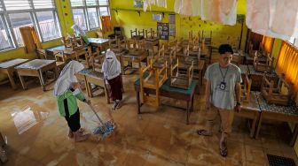 Pelajar didampingi guru membersihkan lantai kelas yang terdampak banjir di SDN 98 Kota Jambi, Kota Baru, Jambi, Senin (7/3/2022). [ANTARA FOTO/Wahdi Septiawan/rwa]