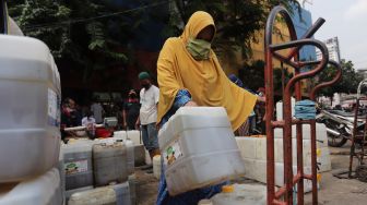 Pedagang membawa jerigen berisi minyak curah saat distribusi minyak goreng curah di Pasar Kebayoran Lama, Jakarta, Rabu (9/3/2022). [Suara.com/Angga Budhiyanto] 