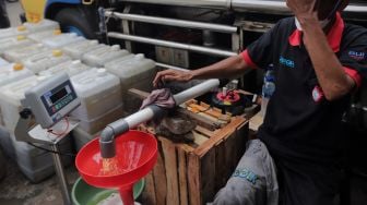 Petugas mengisi jerigen dengan minyak curah saat distribusi minyak goreng curah di Pasar Kebayoran Lama, Jakarta, Rabu (9/3/2022). [Suara.com/Angga Budhiyanto] 