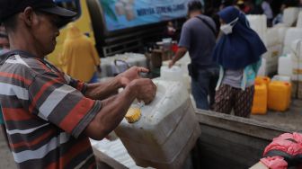 Pedagang membawa jerigen berisi minyak curah saat distribusi minyak goreng curah di Pasar Kebayoran Lama, Jakarta, Rabu (9/3/2022). [Suara.com/Angga Budhiyanto] 