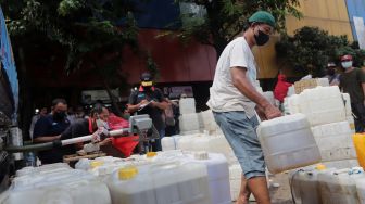 Petugas menata jerigen berisi minyak curah saat distribusi minyak goreng curah di Pasar Kebayoran Lama, Jakarta, Rabu (9/3/2022). [Suara.com/Angga Budhiyanto] 