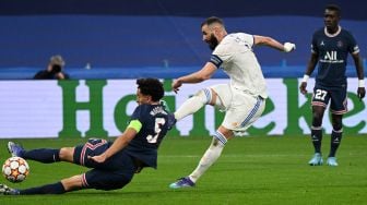 Pemain depan Real Madrid asal Prancis Karim Benzema menendang bola untuk mencetak gol melewati bek Paris Saint-Germain Marquinhos selama pertandingan sepak bola liga kedua babak 16 besar Liga Champions antara Real Madrid melawan Paris Saint-Germain di Stadion Santiago Bernabeu,  Kamis (10/3/2022) dini hari WIB. GABRIEL BOUYS / AFP