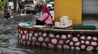 Pedagang berjualan meski banjir menggenangi Pasar Waru, Sidoarjo, Jawa Timur, Jumat (11/3/2022). ANTARA FOTO/Umarul Faruq


