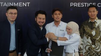 Pendiri Leslar Entertainment Lesti Kejora (kedua kanan) dan Rizky Billar (tengah) bersalaman dengan Presiden Direktur Prestige Motorcars Rudy Salim (kedua kiri) saat penandatanganan akuisisi Leslar Entertainment di Prestige Image Corp, Pluit, Jakarta, Jumat (11/3/2022). [Suara.com/Angga Budhiyanto]