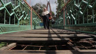 Warga berjalan melintasi Jembatan Wiratman, Kelurahan Srengseng Sawah, Jakarta, Sabtu (12/3/2022). [Suara.com/Angga Budhiyanto]