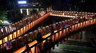 Sejumlah warga berfoto di Jembatan Penyeberangan Orang (JPO) Pinisi Karet-Sudirman, Jakarta, Sabtu (12/3/2022). [Suara.com/Angga Budhiyanto]