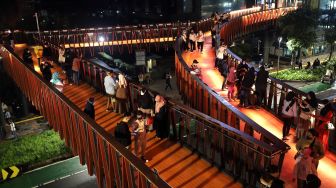 Sejumlah warga berfoto di Jembatan Penyeberangan Orang (JPO) Pinisi Karet-Sudirman, Jakarta, Sabtu (12/3/2022). [Suara.com/Angga Budhiyanto]