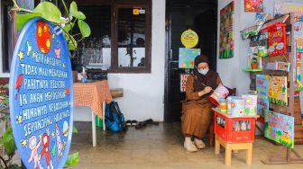 Lani Cahyaningsari (48) menyelesaikan pembuatan kerajinan lukis di atas media kaleng bekas di Kaleng Lani, Depok, Jawa Barat, Minggu (13/3/2022). [Suara.com/Septian]