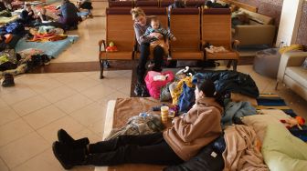 Wanita dan anak-anak mengungsi di stasiun kereta api kota Lviv, Ukraina, Jumat (11/3/2022). [Yuriy Diachyshyn / AFP]