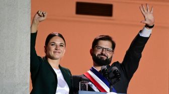 Presiden baru Chili, Gabriel Boric dan pacarnya Irina Karamanos menyambut para pendukung mereka setelah berpidato di Istana La Moneda di Santiago, Chili, Jumat (11/3/2022). [MARTIN BERNETTI / AFP]
