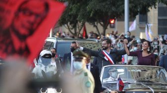 Presiden baru Chili, Gabriel Boric dan Menteri Dalam Negerinya Izkia Siches menyapa para pendukungnya saat tiba di Istana La Moneda setelah upacara pelantikannya di Santiago, Chili, Jumat (11/3/2022). [Pablo Vera / AFP]