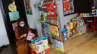 Lani Cahyaningsari (48) menyelesaikan pembuatan kerajinan lukis di atas media kaleng bekas di Kaleng Lani, Depok, Jawa Barat, Minggu (13/3/2022). [Suara.com/Septian]