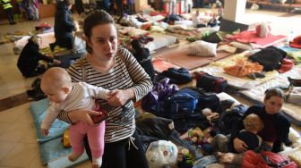 Wanita dan anak-anak mengungsi di stasiun kereta api kota Lviv, Ukraina, Jumat (11/3/2022). [Yuriy Diachyshyn / AFP]