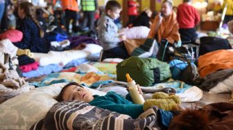 Wanita dan anak-anak mengungsi di stasiun kereta api kota Lviv, Ukraina, Jumat (11/3/2022). [Yuriy Diachyshyn / AFP]