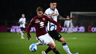 Bek Torino Cristian Ansaldi (tengah) membawa bola di sekitar pemain depan Inter Milan Joaquin Correa saat pertandingan sepak bola Serie A Liga Italia antara Torino dan Inter Milan di stadion Olimpiade, Turin, Italia, Sabtu (13/3/2022). [Marco BERTORELLO / AFP]
