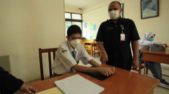 Pelajar didampingi pengajar mengikuti ujian sekolah berbasis nasional di SMA SLBA Pembinaan Tingkat Nasional Jakarta, Senin (14/3/2022). [ANTARA FOTO/Reno Esnir/aww]