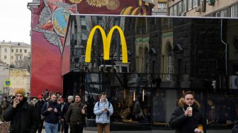 Orang-orang melintas di depan restoran McDonald's di Pushkinskaya Square di pusat kota Moskow, Rusia, Minggu (13/3/2022). [AFP]