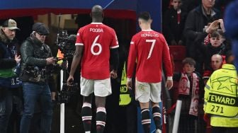 Gelandang Manchester United Paul Pogba (kiri) dan striker Manchester United Cristiano Ronaldo (kanan) langsung pergi setelah peluit akhir dibunyikan dalam pertandingan leg kedua babak 16 besar Liga Champions UEFA antara Manchester United melawan Atletico Madrid di Old Trafford, Rabu (16/3/2022) dini hari WIB. Paul ELLIS / AFP
