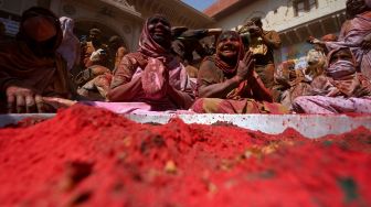 Para janda yang berlumuran Gulal (bubuk warna) duduk di dalam kuil saat mereka berpartisipasi dalam perayaan Holi di sebuah kuil di Vrindavan, India, Selasa (15/3/2022). [Money SHARMA / AFP]