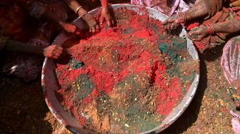 Para janda duduk mengelilingi nampan yang berisi Gulal (bubuk warna) saat mereka berpartisipasi dalam perayaan Holi di sebuah kuil di Vrindavan, India, Selasa (15/3/2022). [Money SHARMA / AFP]