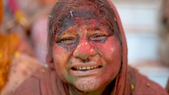 Seorang janda berpose saat berpartisipasi dalam perayaan Holi di sebuah kuil di Vrindavan, India, Selasa (15/3/2022). [Money SHARMA / AFP]