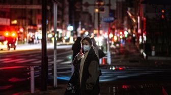 Seorang wanita berbicara melalui gawainya di sebuah jalan perumahan saat pemadaman listrik  setelah gempa berkekuatan 7,3 SR mengguncang wilayah Jepang Timur di Tokyo, Jepang, Kamis (17/3/2022). [Philip FONG / AFP]