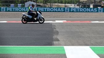 Petugas mengendarai sepeda motor di batas aspal baru (kiri) dan aspal lama (kanan) Pertamina Mandalika International Street Circuit, di Lombok Tengah, NTB, Kamis (17/3/2022). ANTARA FOTO/Andika Wahyu